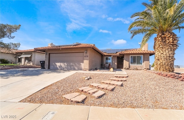 view of front of house with stucco siding, concrete driveway, roof mounted solar panels, a garage, and a tiled roof