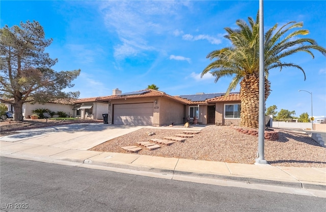 ranch-style home featuring a garage, driveway, a tiled roof, roof mounted solar panels, and stucco siding