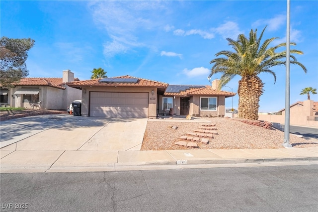 view of front of house featuring an attached garage, a tile roof, concrete driveway, roof mounted solar panels, and stucco siding