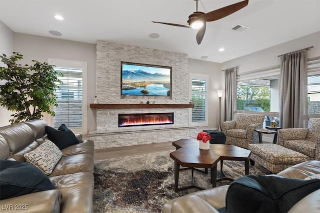 living area featuring a fireplace, wood finished floors, visible vents, and recessed lighting