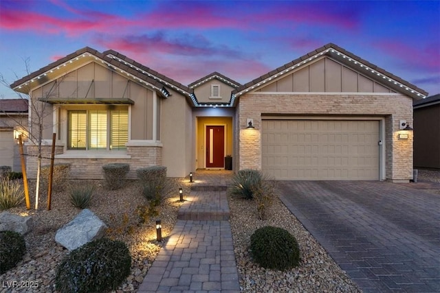 view of front of house featuring a garage, stone siding, and decorative driveway