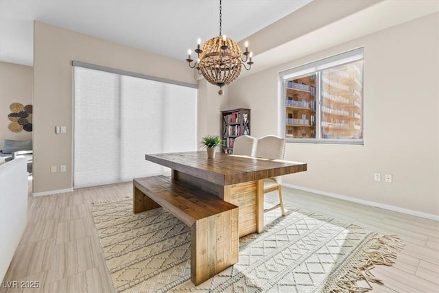 dining space with light wood finished floors, baseboards, and a notable chandelier