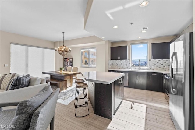 kitchen featuring a kitchen island, appliances with stainless steel finishes, light countertops, and backsplash