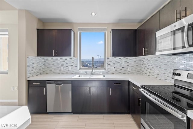 kitchen featuring stainless steel appliances, light countertops, a sink, and dark brown cabinets