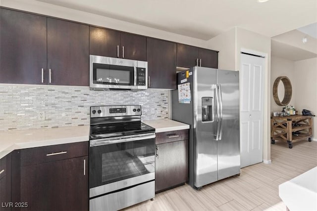 kitchen with stainless steel appliances, dark brown cabinets, backsplash, and light countertops