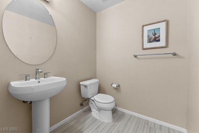 half bath featuring toilet, baseboards, and wood finished floors