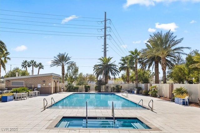 pool with a community hot tub, a patio area, and fence