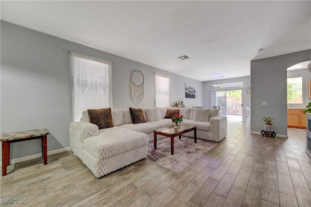 living room featuring light wood-style floors, visible vents, and baseboards