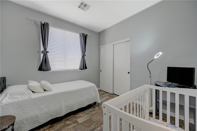 bedroom with a closet, visible vents, and wood finished floors