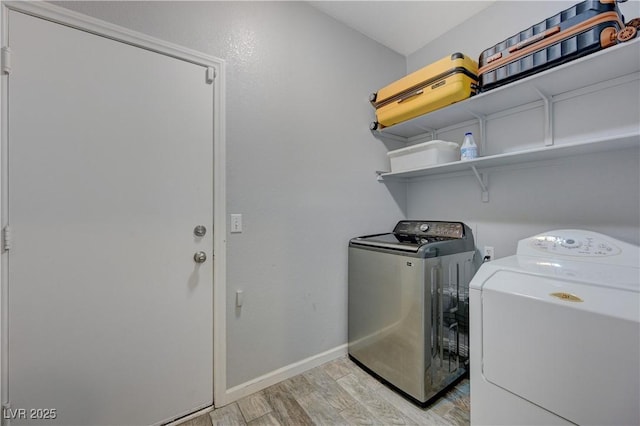 laundry room featuring baseboards, laundry area, washer and clothes dryer, and light wood-style floors