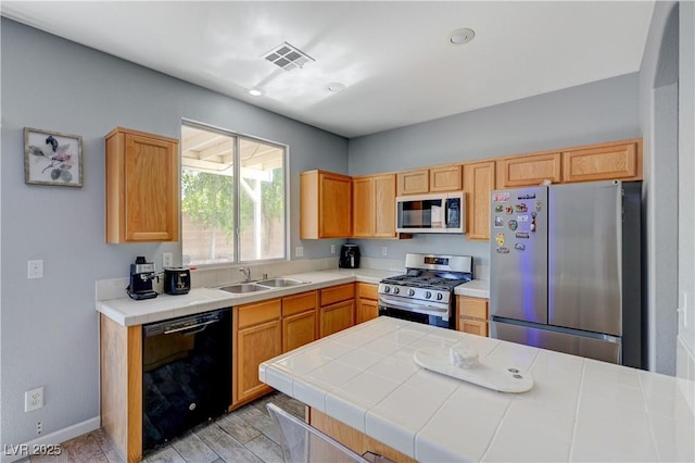 kitchen featuring baseboards, visible vents, tile counters, appliances with stainless steel finishes, and a sink