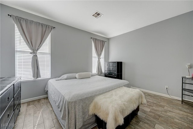 bedroom featuring visible vents, baseboards, and wood finished floors