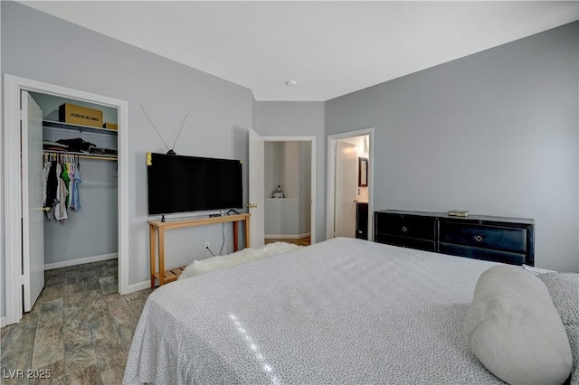 bedroom featuring light wood finished floors, baseboards, a walk in closet, and a closet