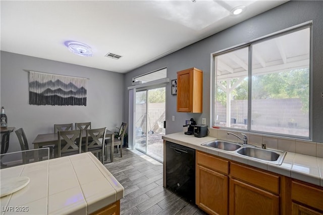 kitchen with dishwasher, tile countertops, a sink, and visible vents