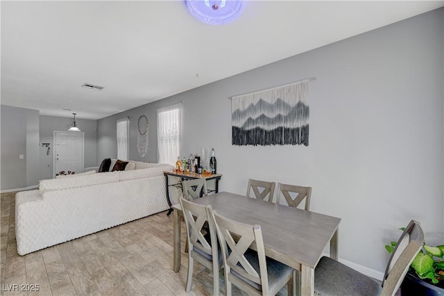 dining area featuring light wood-type flooring, visible vents, and baseboards