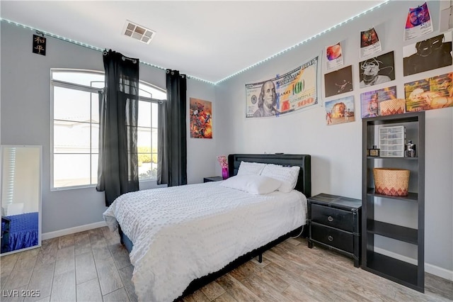 bedroom with wood finished floors, visible vents, and baseboards