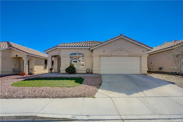 mediterranean / spanish-style house featuring an attached garage, a tiled roof, concrete driveway, and stucco siding