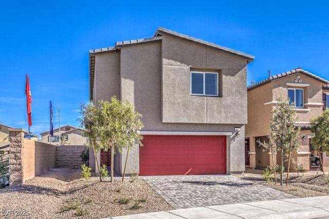 view of front facade with an attached garage, fence, decorative driveway, and stucco siding