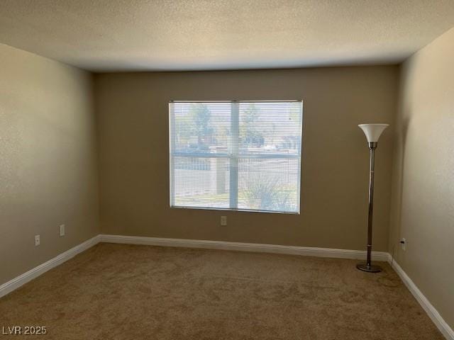 empty room featuring carpet flooring, a textured ceiling, and baseboards