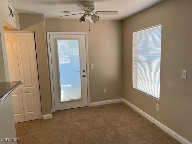 doorway featuring ceiling fan, carpet flooring, visible vents, and baseboards