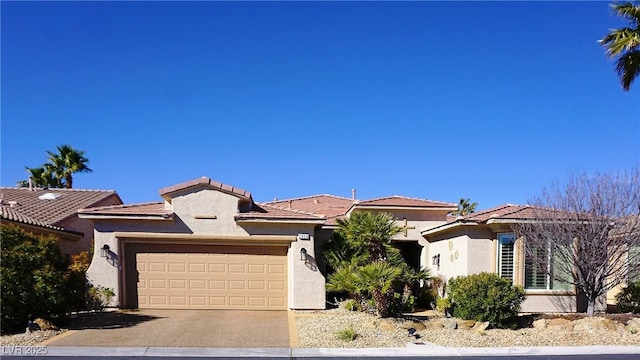 view of front of property featuring a garage, a tiled roof, concrete driveway, and stucco siding