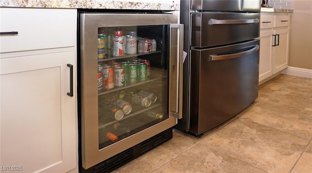 room details with freestanding refrigerator, beverage cooler, and white cabinetry