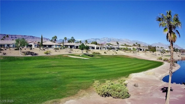 view of home's community with a water and mountain view, golf course view, and a lawn