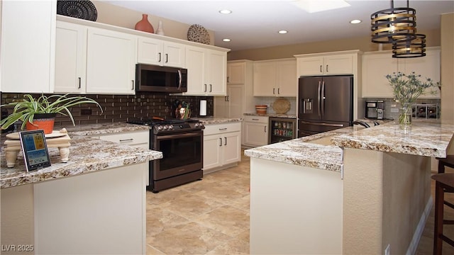 kitchen featuring appliances with stainless steel finishes, beverage cooler, white cabinetry, and a breakfast bar area