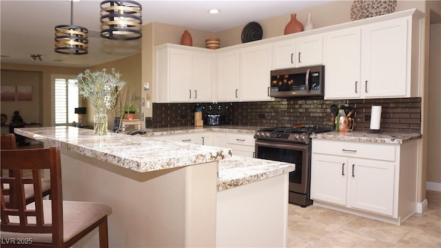 kitchen featuring pendant lighting, appliances with stainless steel finishes, a breakfast bar, and white cabinets