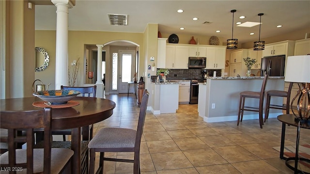 kitchen featuring visible vents, appliances with stainless steel finishes, white cabinets, and decorative light fixtures