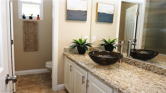 bathroom with baseboards, vanity, toilet, and tile patterned floors