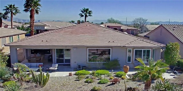 back of house featuring a patio area, a tiled roof, and stucco siding