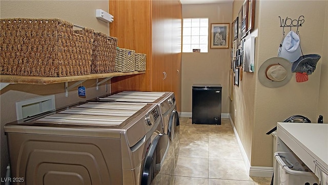 kitchen featuring light tile patterned flooring, washing machine and dryer, and baseboards