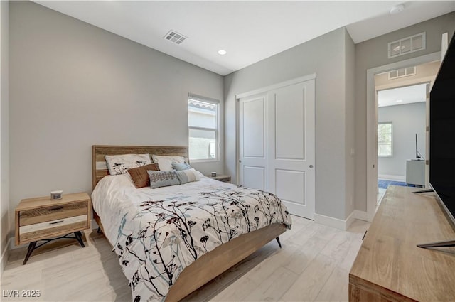 bedroom featuring a closet, light wood-type flooring, and visible vents