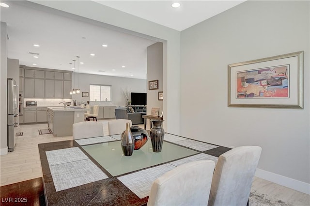 dining room with baseboards, light wood finished floors, and recessed lighting