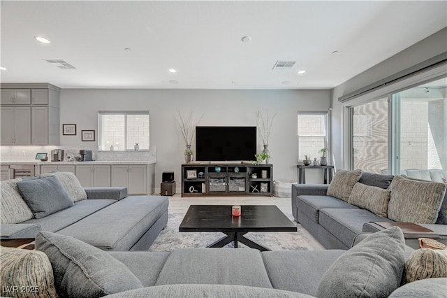 living area with a healthy amount of sunlight, visible vents, and recessed lighting