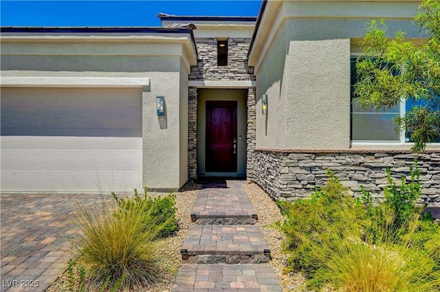 property entrance featuring a garage, stone siding, and stucco siding