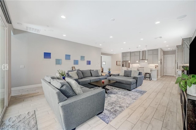 living room featuring wood tiled floor, visible vents, baseboards, and recessed lighting