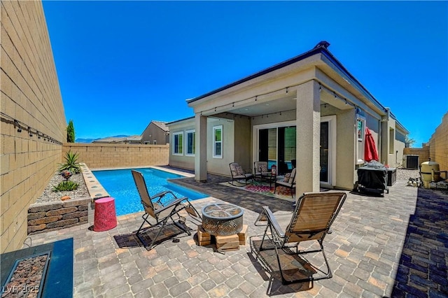 view of pool with a fenced backyard, a fire pit, cooling unit, and a patio