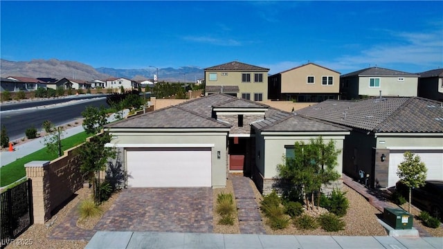 view of front of home featuring a mountain view, a garage, decorative driveway, a residential view, and stucco siding