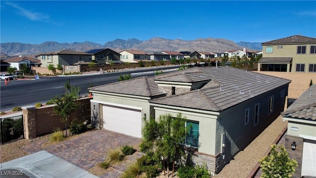 exterior space featuring stone siding, a residential view, a mountain view, and stucco siding