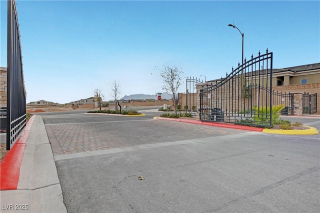 view of road with street lights, a gate, and curbs