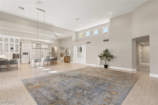 entryway with arched walkways, baseboards, visible vents, and a high ceiling