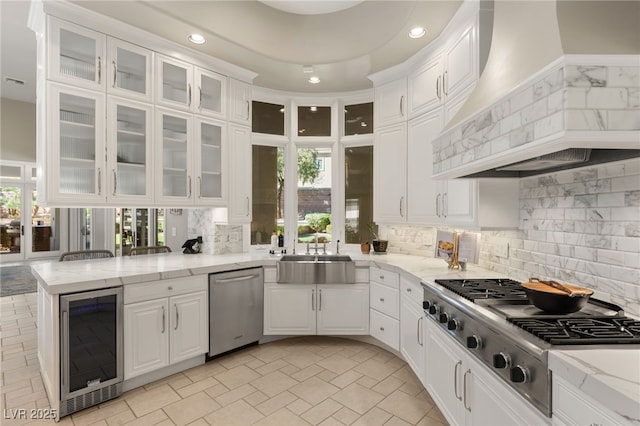 kitchen featuring beverage cooler, appliances with stainless steel finishes, white cabinets, and custom range hood