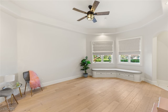 unfurnished room featuring arched walkways, baseboards, ceiling fan, and light wood finished floors