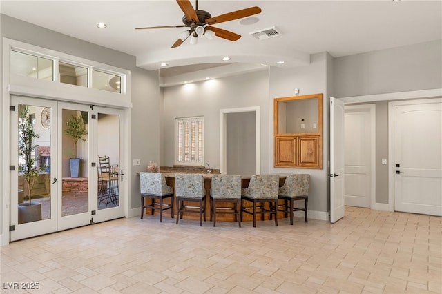 kitchen with a breakfast bar area, recessed lighting, visible vents, baseboards, and french doors