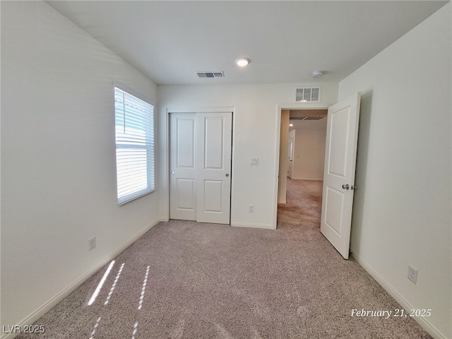 unfurnished bedroom with baseboards, visible vents, a closet, and light colored carpet