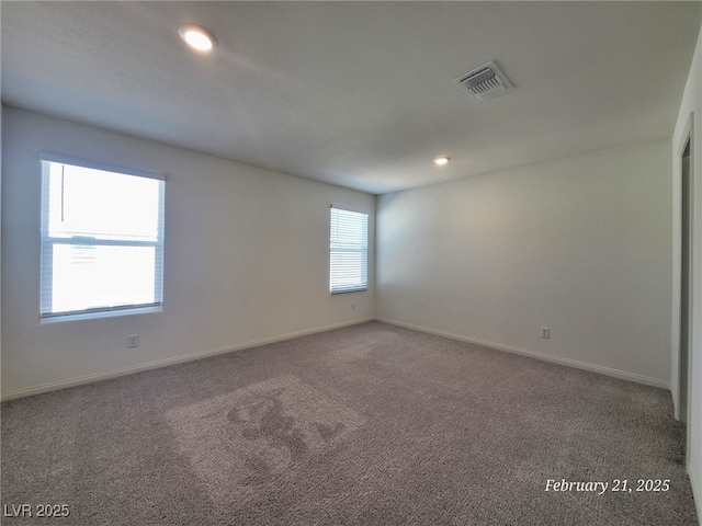 carpeted empty room with baseboards, visible vents, and recessed lighting