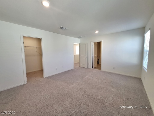 unfurnished bedroom with light carpet, baseboards, visible vents, a spacious closet, and recessed lighting