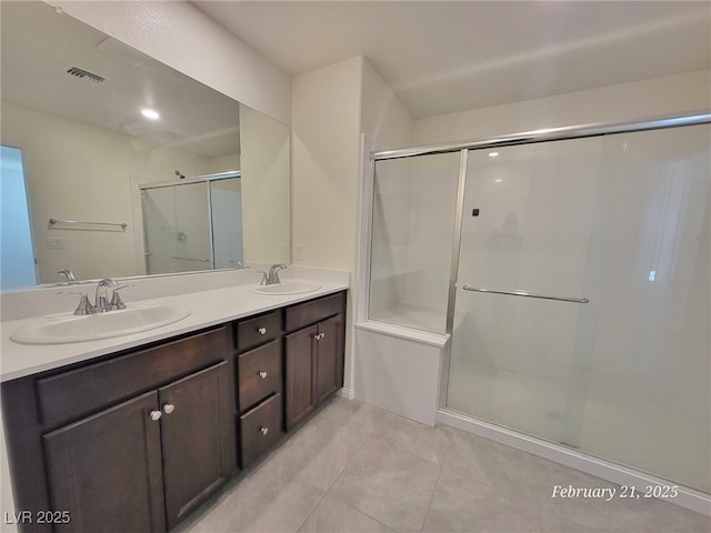 full bath with a stall shower, visible vents, a sink, and double vanity